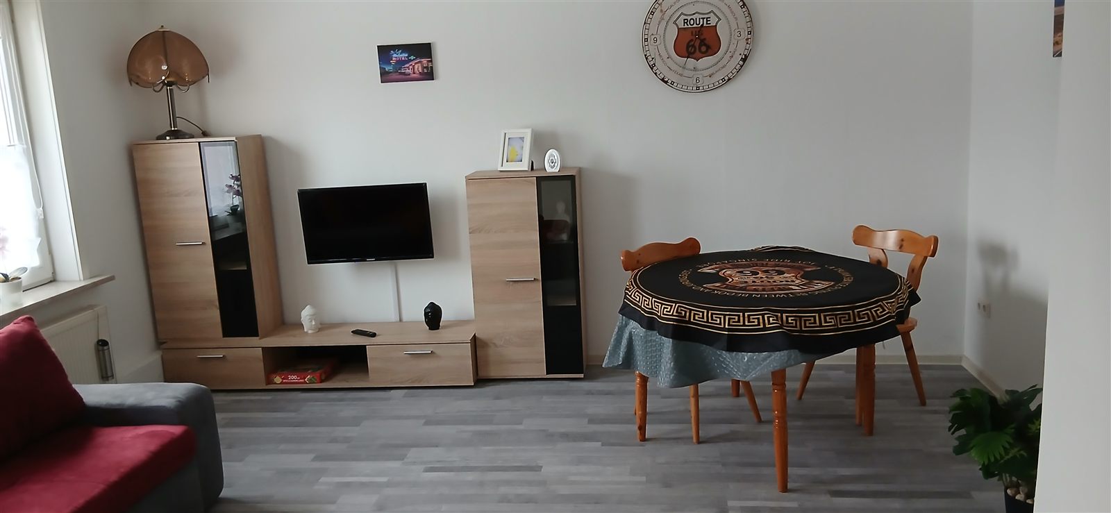 Wohnzimmer mit Sofa, Esstisch und Fernseher